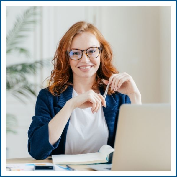 Professional financial advisor smiling sitting at desk with laptop and documents