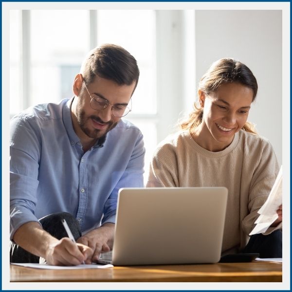 Happy couple at laptop reviewing home budget and paperwork together